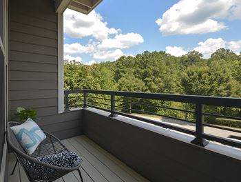 A balcony with a chair and a view of the woods
